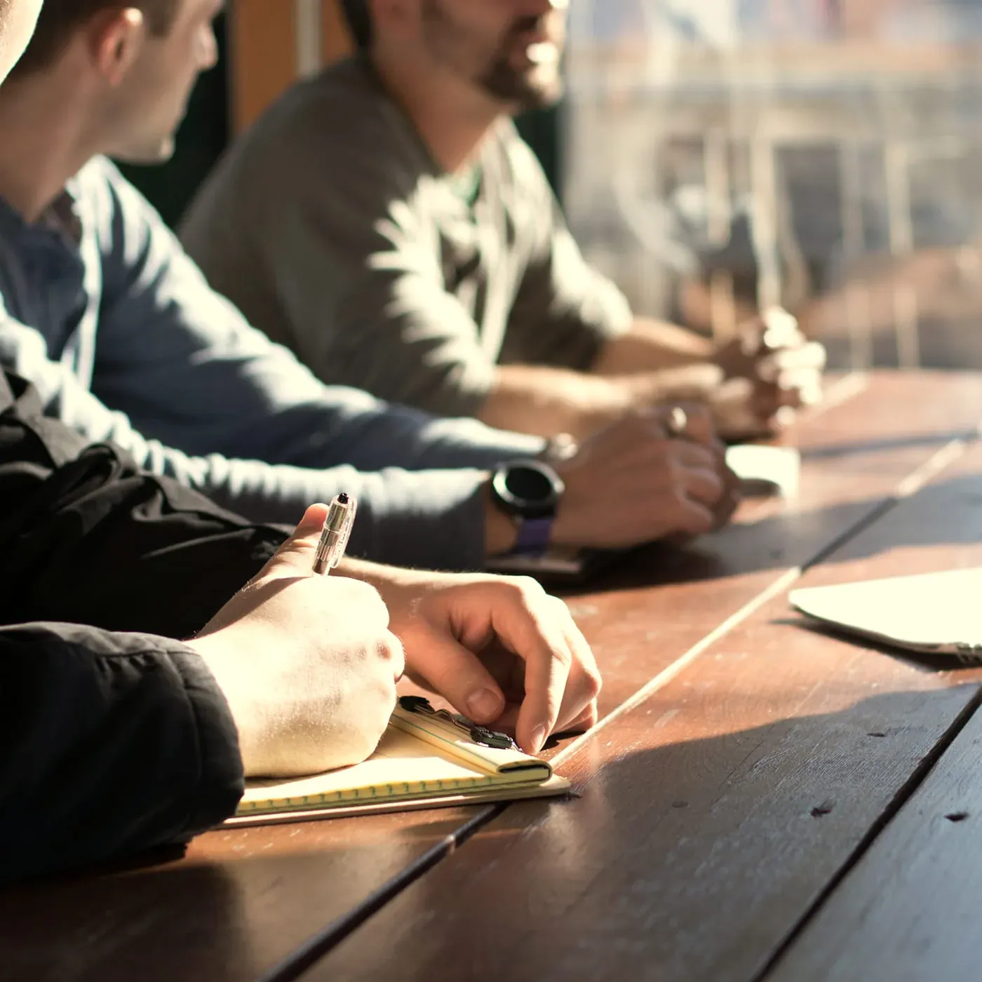 A team working through a digital strategy around a wooden table, taking notes